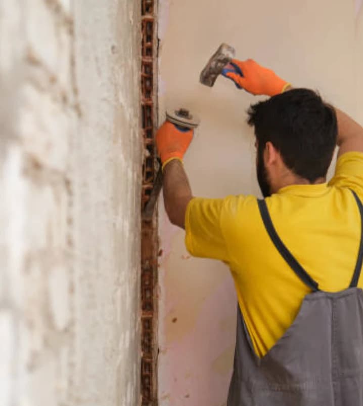 Oficial de construcción verificado de Maestro reparando un muro de ladrillo durante una remodelación en Bogotá